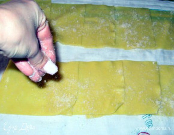 Присыпать тёртым пармезанским сыром. Кроме того, что сыр придаст дополнительный вкус пасте, он ещё и подсушит её, начинка пристанет лучше и будет легче закрутить каннелони.

