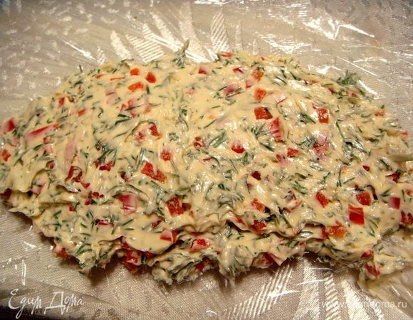 Сначала приготовим цветное масло. Для этого сливочное масло комнатной температуры смешаем с пропущенным через пресс чесноком, мелко порезанным укропчиком и мелко порезанным сладким перцем. Выложим на полиэтиленовую пленку. 