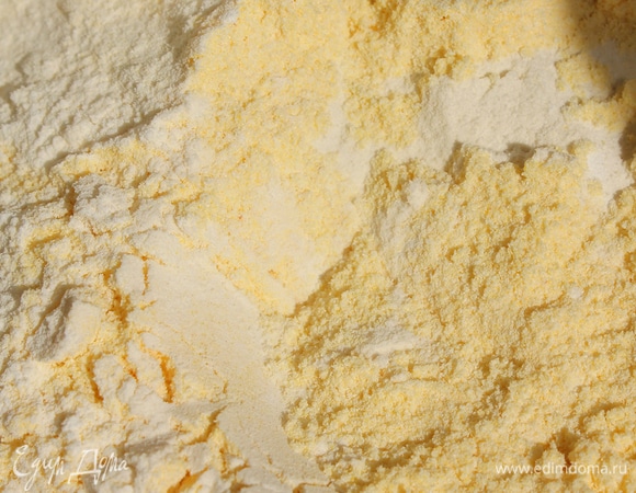 В отдельной миске просеять кукурузную и пшеничную муку. Добавить крахмал с разрыхлителем. Половину мучной смеси смешать со сливками, затем замешать все с маслом и желтками. Частями ввести оставшуюся муку, хорошо перемешать.