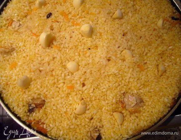 Примерно за 5 минут до выключения огня, когда рис в состоянии аль денте (готовый снаружи и твердоватый внутри) я втыкаю по всей поверхности сковороды очищенные зубчики чеснока. Если бы это был казан на природе, то мы обычно вглубь плова вставляем целую головку чеснока, очищенную только от внешней чешуи. Выравниваем поверхность ложкой (чтобы чеснок был внутри риса), накрываю плов крышкой и выдерживаю ещё примерно 5 минут. 