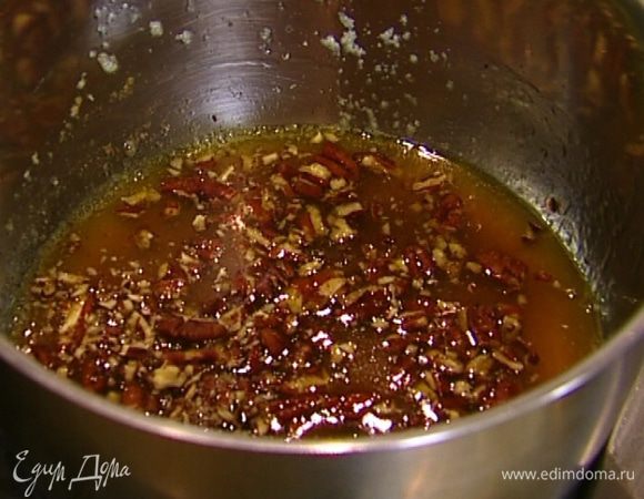 Приготовить сироп: в оставшееся растопленное сливочное масло добавить мед и, помешивая, прогревать на небольшом огне в течение 2–3 минут, затем всыпать орехи, перемешать и еще немного прогреть.<br />
Подавать оладьи с ореховым сиропом.