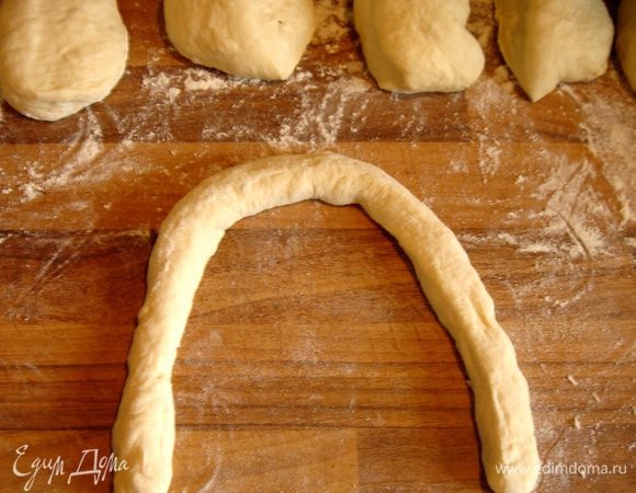 Воду смешать с содой и нагреть до кипения.Тесто разделить на 12 частей.Каждую часть скатать в колбаску,шириной не более 1 см.Концы должны быть тонкими,середина-чуть толще.Колбаску можно немного скрутить,как жгут.Уложить жгут буквой U концами к себе.