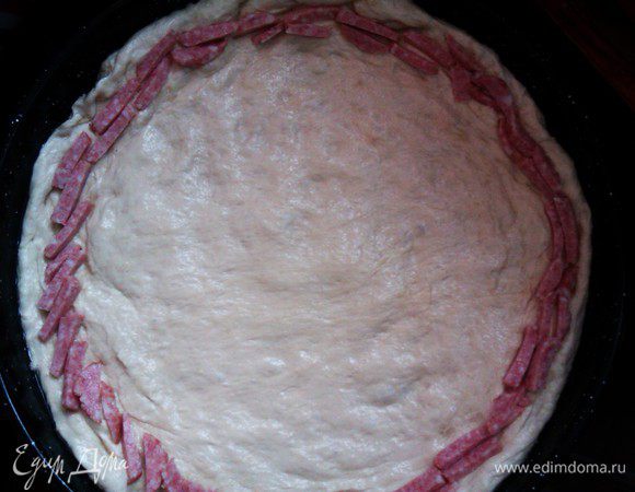 Форму смажьте растительным маслом, раскатайте тесто или разровнять руками по форме. Часть колбасы нарежьте соломкой.