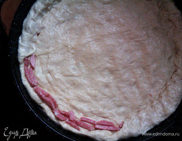 Нарезанную колбасу выложите по краю и заверните тесто, сделайте вкусный бортик.