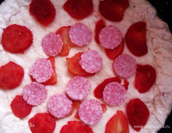 На тесто выложите помидоры, сверху — колбасу и посыпьте сверху сыром. Запекайте 30 минут в разогретой духовке. Дрожжевое тесто для пиццы будет мягким, но плотным, начинка не будет выпадать. Приятного аппетита! 