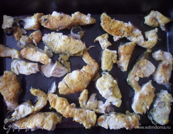 Разобрать кусочки жареной рыбы от больших костей и выложить на противень.