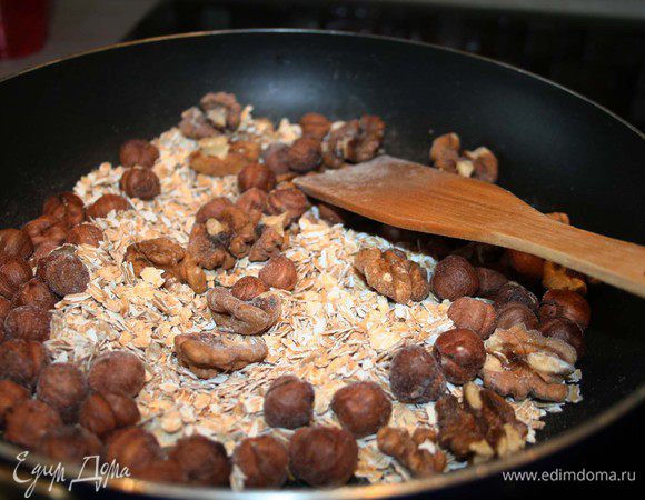Прокалить орехи и хлопья на горячей сковороде.