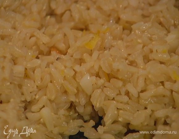 Выложить в сковороду с чесноком рис, влить оставшееся оливковое масло, перемешать.