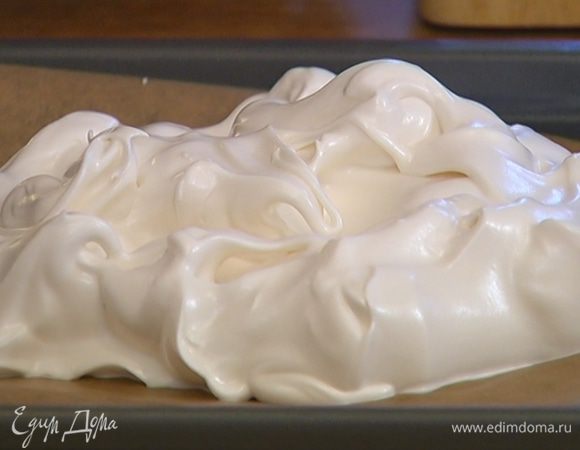 Выстелить противень бумагой для выпечки и выложить на нее белковую массу, сформировав одну или несколько меренг с неровными, волнистыми краями.