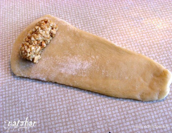 Посередине расширенного конца пласта выложить десертную ложечку ореховой начинки и сформировать из неё "колбаску".