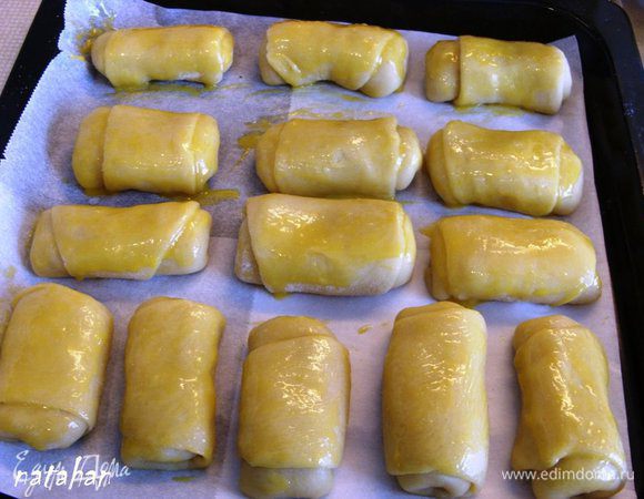 Выложить рулетики на застеленный пергаментом противень. Смазать их взбитым яичным желтком. Поставить противень в нагретую до 200 градусов духовку на 20 минут.
