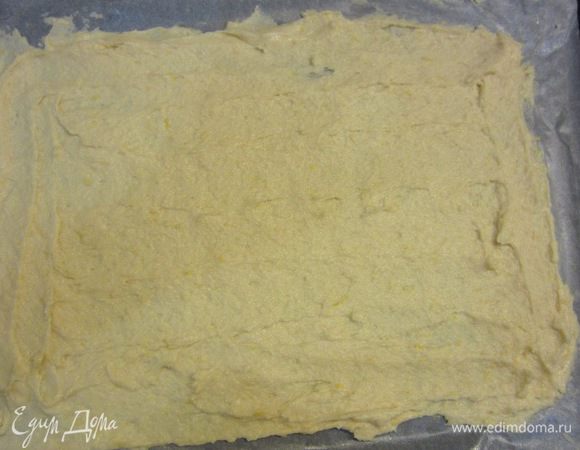 Теперь необходимо выпекать коржи. Чтобы меньше возиться - я сделал два больших прямоугольных коржа и разрезал их пополам, но вы можете выпечь три круглых. Постелите на противень пергаментную бумагу, размажьте половину теста ровным слоем. Выпекайте в предварительно разогретой до 180 градусов духовке около 10 минут.