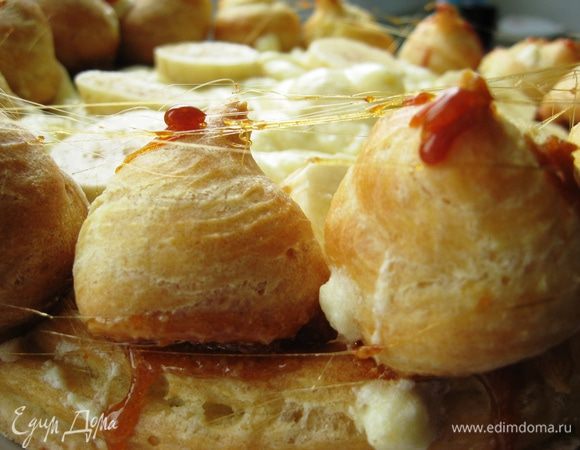 Аккуратно обмакиваем в карамель и выкладываем поверх основы. Серединку украшаем оставшимся кремом. И все обволакиваем карамельными нитями. Отправляем в холодильник на несколько часов. 