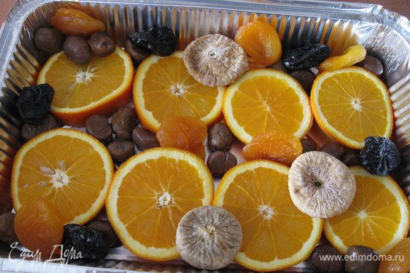 Форму для запекания смазать маслом, выложить кружочки апельсина, между ними положить каштаны и сухофрукты.