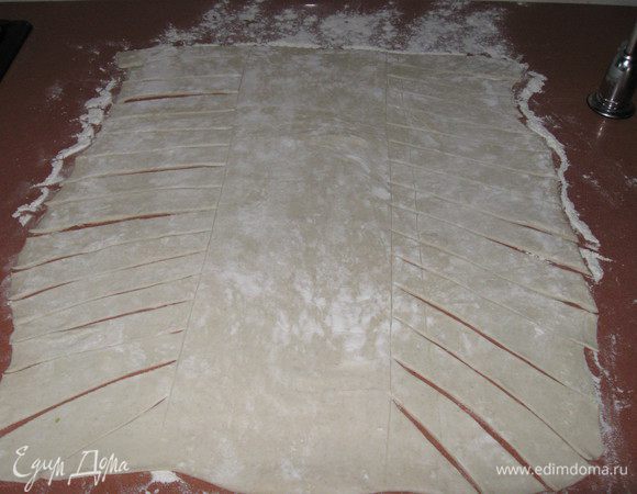 Выкладываем тесто на противень(я делала на столе), застеленный бумагой для выпечки. Ножом(не сильно, чтобы не прорезать) делим тесто на три части. На двух крайних частях нарезаем тесто под углом на полоски примерно 1.5 см.