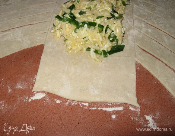 На среднюю часть теста выкладываем начинку, не доходя 4-5 см до краев( по длине), обрезаем кончики теста в начале и конце.Заворачиваем край средней части теста на начинку. 