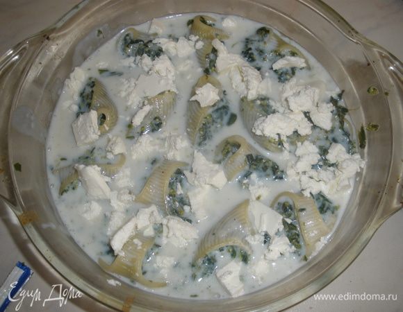 Приготовить соус - сливочное масло растопить, добавить муку. Влить молоко и венчиком все размешать, чтобы не было комочков. Посолить, поперчить, добавить щипотку мускатного ореха. Дать покипеть 2 минуты на медленном огне. Как загустеет убрать с огня. Залить пасту соусом. Сверху разбросать кусочки феты. Выпекать около 20 минут при температуре 200 градусов