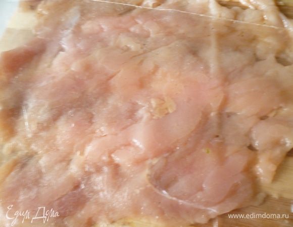 Достать из холодильника мясо.Мелкие кусочки отложить в отдельную посуду,убрать лавровый лист.Теперь берем доску,накрываем ее пленкой и выкладываем сначала одно филе,если вы любите посоленей,то слегка присолите.Для моей семьи достаточно соли которая содержится в соевом соусе и сыре. и отбиваем его через пленку тупой стороной молоточка или скалкой.Рядом выкладываем второе филе и также его отбиваем.У нас получается длинный пласт отбитого мяса.