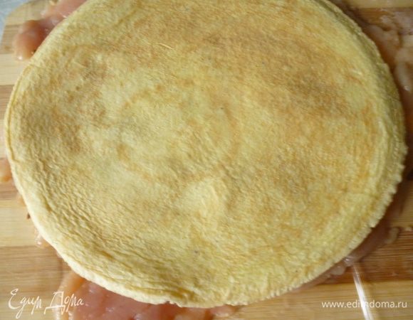 Снимаем верхнюю пленку.На одну половину мясного пласта выкладываем блинчик.