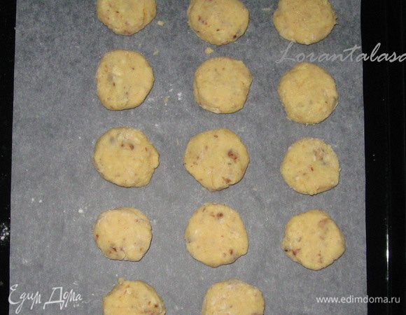 Добавить к этой смеси муку и пекарский порошок и хорошо перемешать, после чего добавить в тесто грецкие орехи и и шоколад. Из теста сделать шарики, которые затем расплющить в лепешечки-печенья и выложить их на противень с пергаментом.