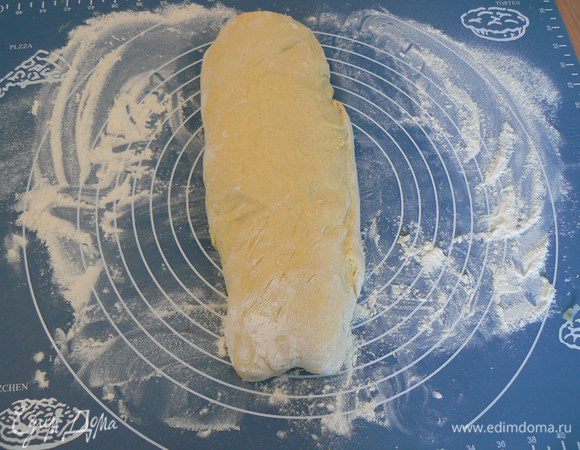 Выложить тесто на разделочную поверхность  присыпанную мукой, распластать  руками в прямоугольник, свернуть нетугим рулетом