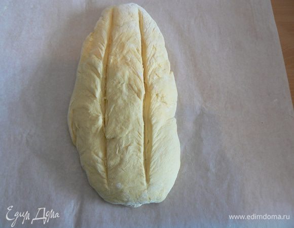 Выложить на противень, застеленный пергаментом.Сделать на поверхности два продольных разреза. Поставить в тёплое место для подъёма. 