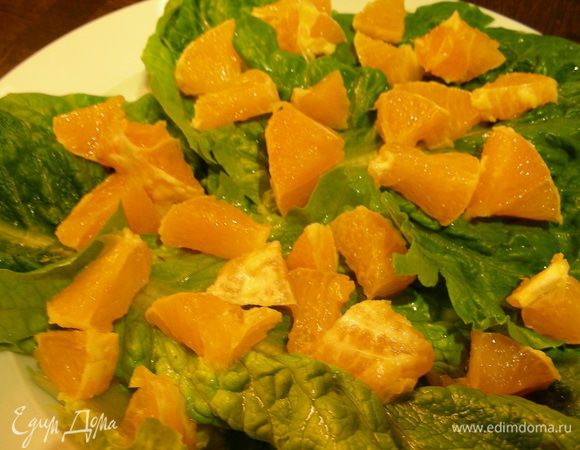 На тарелку выкладываем салатные листья. На них апельсин.

