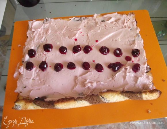 Разворачиваем остывший рулет и начиняем кремом, сверху кладём вишенки.