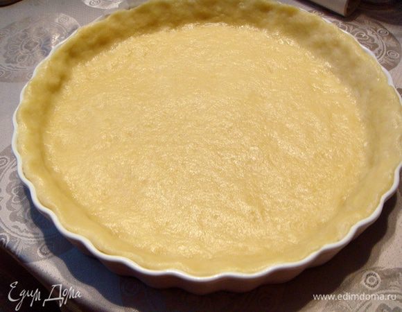 Выложить в круглую форму пергаментную бумагу, а на нее тесто. Разровнять его руками так, чтобы получилась «корзинка» с бортиками.