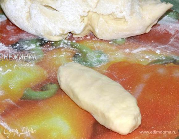 Формируем булочки. На присыпанную мукой поверхность выкладываем тесто. Отделяем небольшой кусочек, делаем из него батончик.