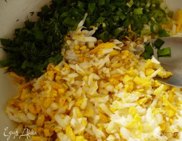 Сначала приготовим начинку. Яйца сварить и натереть на крупной терке или нарезать кубиком. Добавить измельченную зелень. На сковородке растопить столовую ложку сливочного масла, добавить к нему столовую ложку растительного масла, перемешать и добавить к яйцам и зелени. Поперчить, посолить и перемешать.