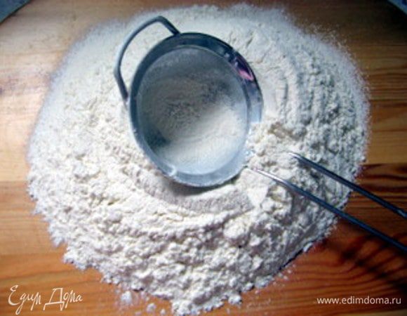 Просеять муку, насыпать горкой на рабочую поверхность.