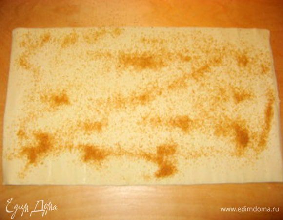 Пласт готового слоёного теста раскрыть на рабочей поверности. Присыпать тростниковым сахаром 

