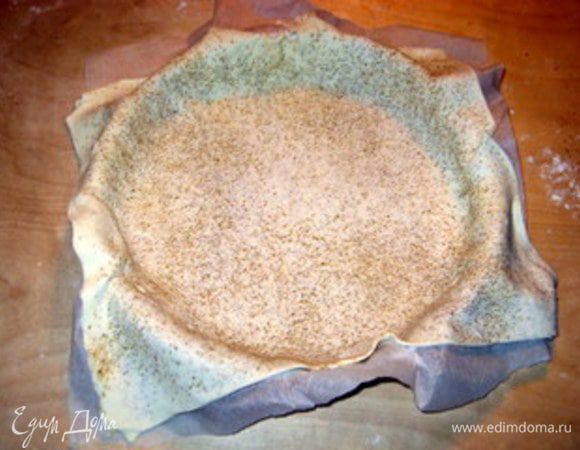 Форму для тарта накрыть пергаментом и разместить в ней первый больший корж.