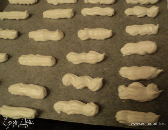 Духовку разогреть до 150градусов, противень застелить бумагой для выпечки. Выложить взбитые белки в кондитерский мешок и отсадить на противень продолговатые полоски на расстоянии друг от друга. 