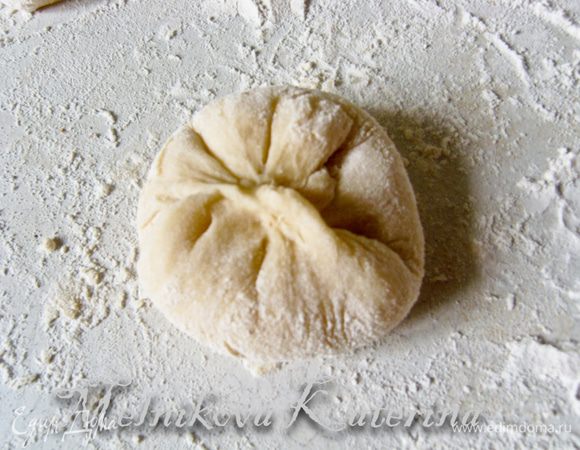 Закрепить булочку "в мешочек", перевернуть гладкой стороной вверх и выложить на противень, выстеленный пекарской бумагой и смазанный сливочным маслом. Таким образом, сформировать все булочки. 