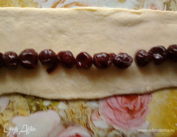 Взять одну часть теста и раскатать в пласт 20 см на 7-8 см. Выложить сверху вишню и свернуть в трубочку. Так же сделать и с остальным тестом.