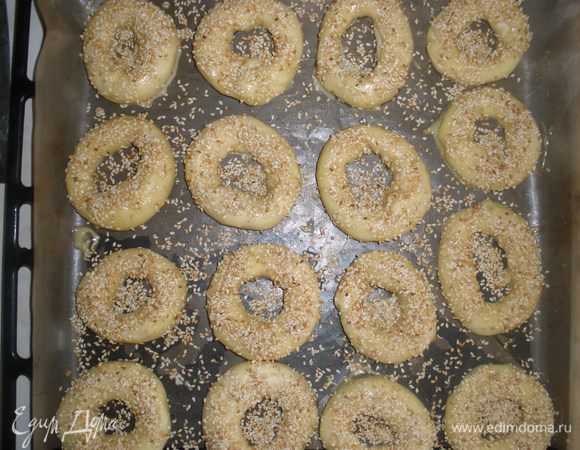 Каждый бублик смазать желтком (в желотк можно капнуть молока, так он будет легче размазываться) и обильно посыпать кунжутом. Выпекать 15-20 минут при температуре 200 градусов. 