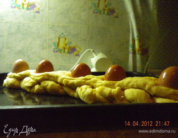 Переложить хлеб на смазанный маслом противень. Наметить 5 гнезд для
яиц, сделать их достаточно глубокими (когда косичка чуть-чуть постоит в теплом месте и поднимется гнезда получатся глубокими). Неокрашенные сваренные  яйца обильно смазать растительным маслом и разложить в гнезда. Поставить наш хлеб в теплое место минут на 20. Затем  Желток смешать с 1 ст.ложкой воды и смазать поверхность хлеба. Посыпать кунжутом и выпекать 40-45 минут при 180 градусах.  Когда хлеб остынет вынуть из него яйца и заменить их на пасхальные.