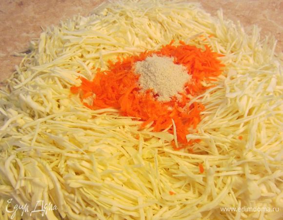 Теперь переложите капусту на стол с целофановой скатертью или как у меня на большую столешницу. Выложите сверху морковь и соль.