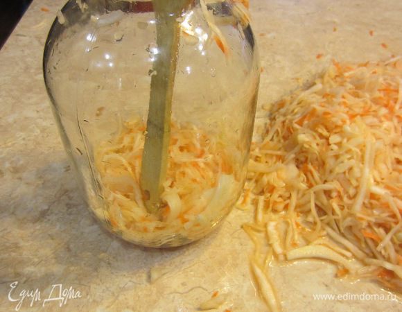 Теперь возьмите чистую трехлитровую банку. Кладите небольшими порциями капусту внутрь и утрамбовывайте ее ручкой от деревянной ложки. Вам не надо очень сильно утрамбовывать и лучше это делать именно ручкой, а не "толкушкой", т.к. именно ручка со своими небольшими размерами, позволит плотно утрамбовать капусту. Делайте утрамбовку тщательно, не прилагая больших усилий.