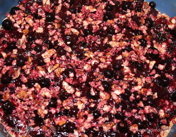 Достать полу-готовый корж из духовки, выложить сверху ягодно-шоколадную массу. Посыпать орешками и целыми ягодами. Выпекать при 190С еще 15 минут.