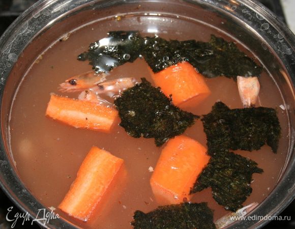 Почистить морковку. Панцири от креветок положить в кастрюльку с водой, туда же добавить морковь и поломанный на кусочки лист нори. Варить бульон 20 минут.   