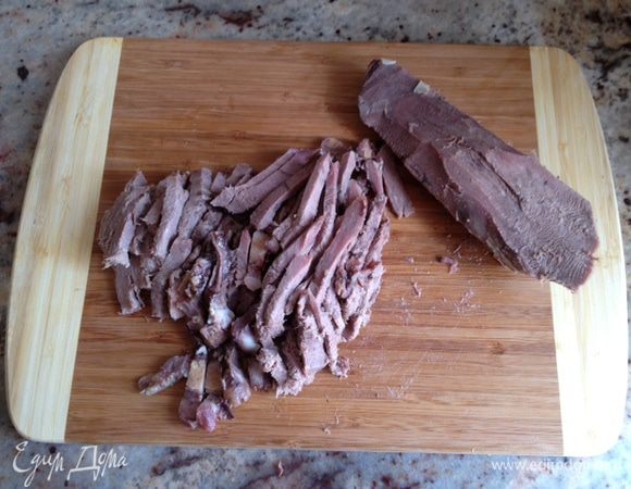  Нарезать тонкими кусочками отваренный и очищенный язык. 