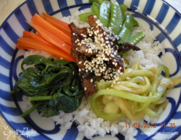 На дно глубокой тарелки  выкладываем рис, в центр мясо, по кругу овощи. Поливаем всё кунжутным маслом, соевым соусом. По желанию посыпаем жгучим перцем и кунжутными семечками. 