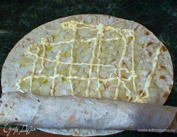 Далее необходимо плотно свернуть лист с нашей рыбой. 
Берем новый лист и кладем отжатый замаринованный лук и майонезную сеточку. Теперь берем первый блин с консервой и кладем на ближний к себе край. Сворачиваем их вместе от себя.