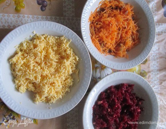 Это слоённый салат. Сначала приготовим слои. Отварную свеклу нужно натереть на мелкой тёрке, отжать её немного и добавить мелко нарубленные грецкие орехи. Морковь и сыр также натереть на мелкой тёрке. Морковь смешать с изюмом, а сыр с чесноком (я пропускала чеснок через чеснокодавилку, можно мелко нарубить). Грецкие орехи, изюм и чеснок ложила " на глаз".