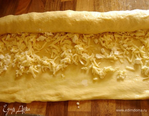 Брынзу натереть на крупной тёрке.Все остатки масла распределить на тесте,затем присыпать всю поверхность прямоугольника брынзой.Свернуть тесто в рулет.