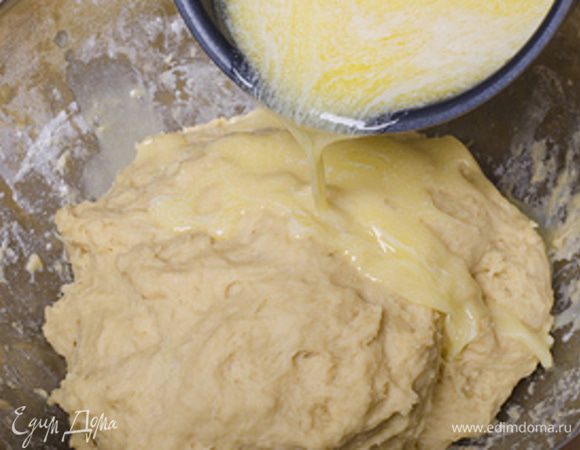 В готовое тесто вливаем постепенно небольшими порциями теплое жидкое сливочное масло, вымешиваем. 