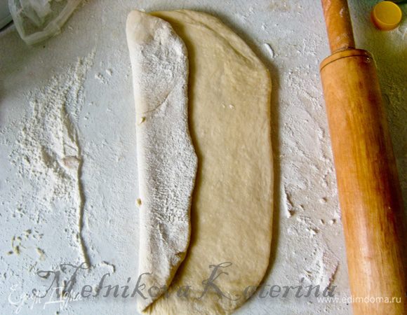 Немного тесто обмять. Разделить на три примерно равные части. Начинаем формирование хлеба. Берем первую часть. Скалкой раскатываем в длинный овал. Левую часть заворачиваем по направлению к центру. 